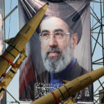 Portrait of Iranian Supreme Leader Mojtaba Khamenei displayed behind Zolfaghar ballistic missiles during a military exhibition.